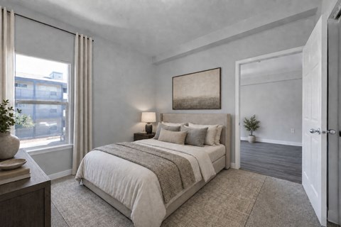 A bedroom with a large bed and a window with curtains.