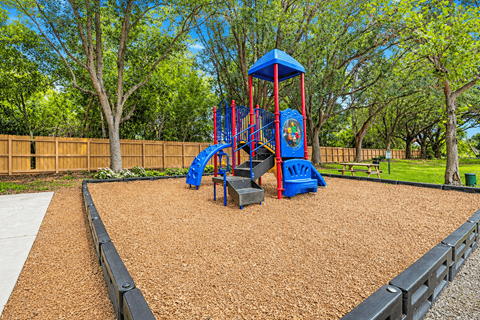 A playground with a blue and red swing set.