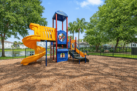 A playground with a yellow slide and a blue tower.