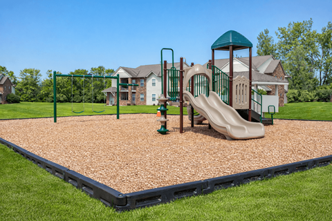 A playground with a slide, swings, and a green tower at Arbors at Hickory Creek Apartments , University Park, Illinois