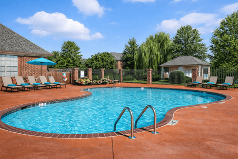 A pool surrounded by a brick patio and a gazebo.