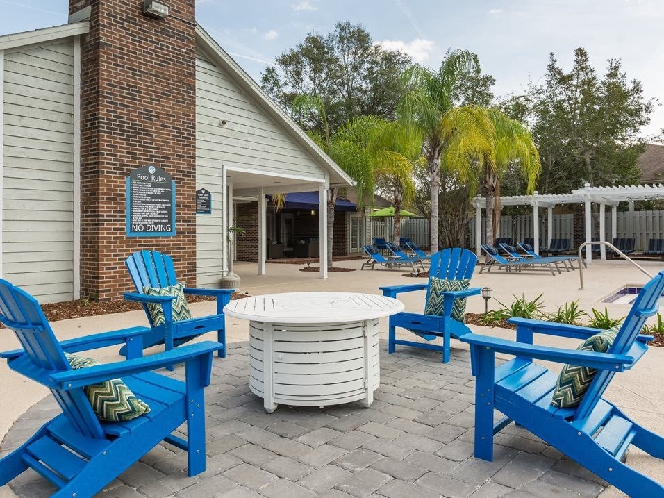 a patio with blue chairs and a table in front of a building
