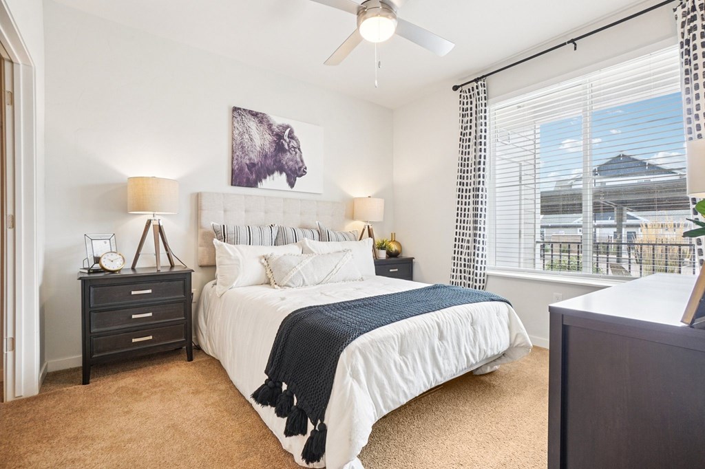 A bedroom with a large bed and a painting of a bison on the wall. at Connect at First Creek Apartments, Denver, CO, 80249