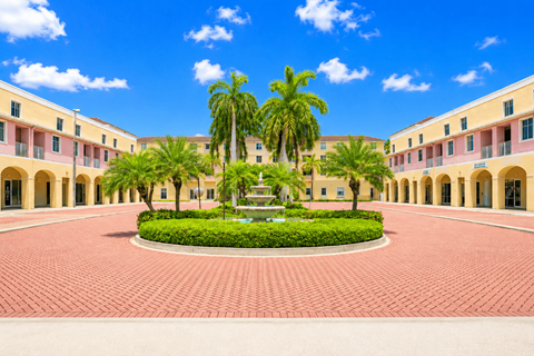 A courtyard with a fountain surrounded by palm trees and buildings.