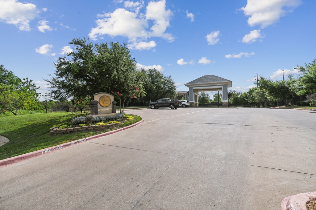 a parking lot with a sign and a building in the background