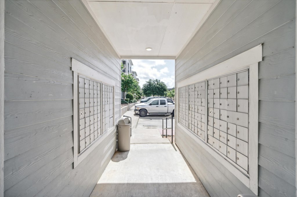 a parking garage with white wood walls and mailboxes and a white car parked outside