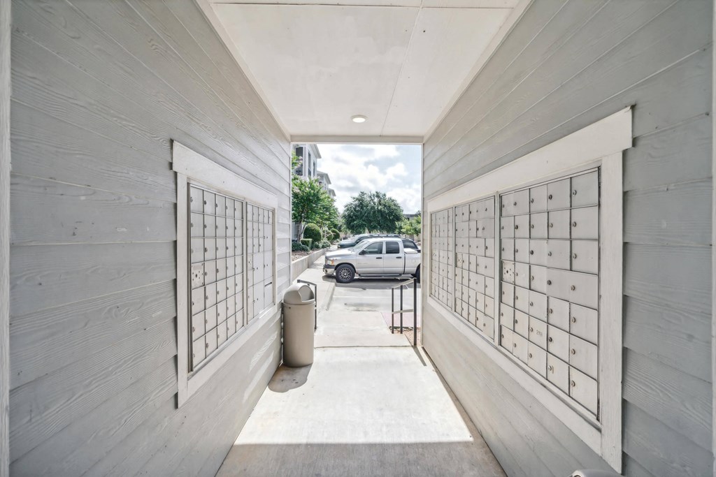 a parking garage with white wood walls and mailboxes and a white car parked outside at St. Augustine Estate, Dallas, TX
