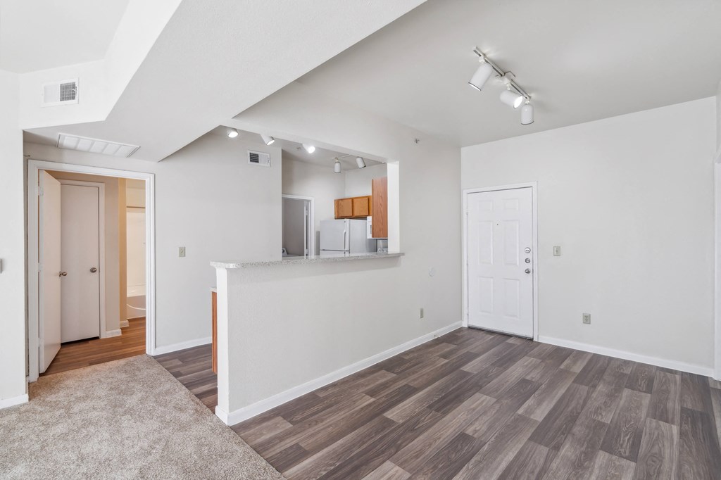 the living room and kitchen of a new home with white walls and wood flooring