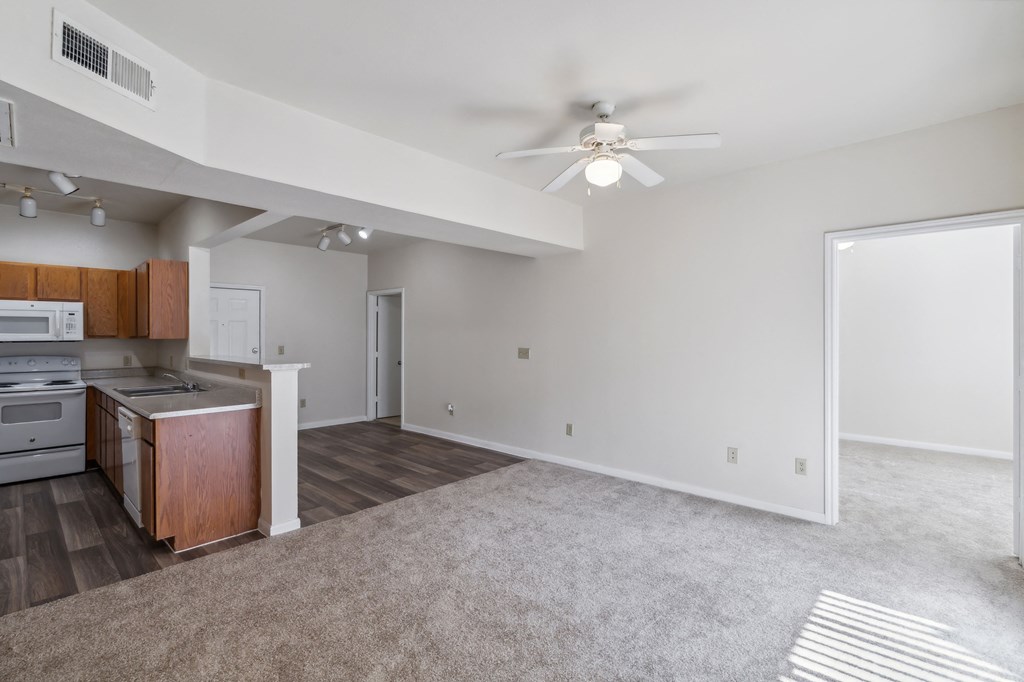 an empty living room and kitchen with a ceiling fan