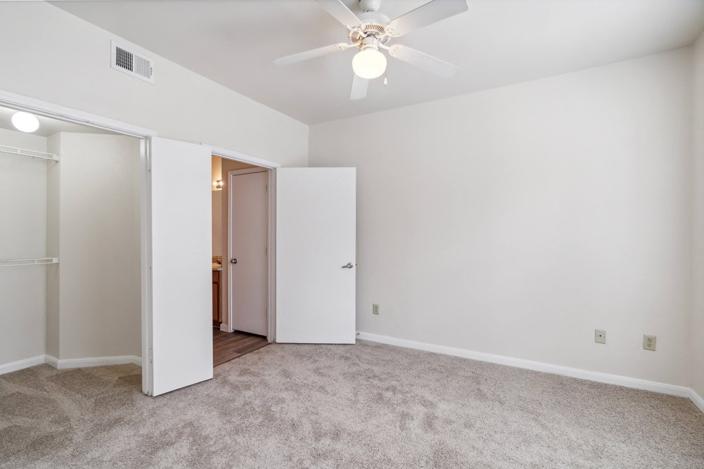 an empty living room with white walls and a ceiling fan
