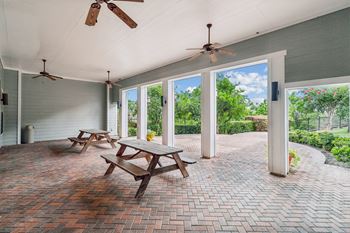 A patio with a table and chairs and a ceiling fan.