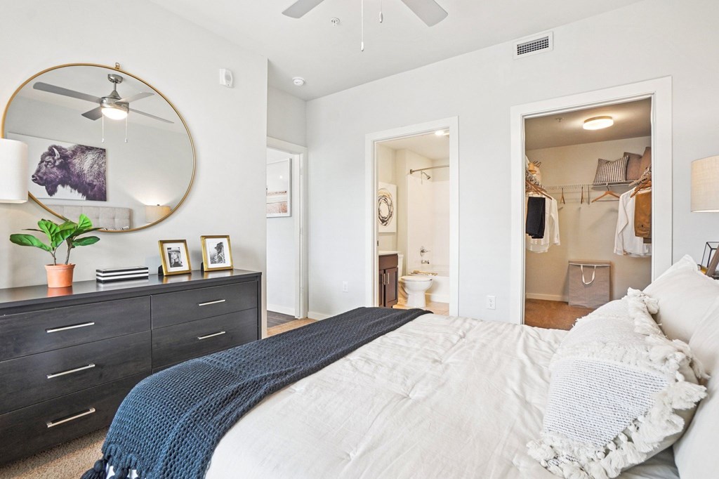 A bedroom with a large bed and a mirror on the wall. at Connect at First Creek Apartments, Denver, CO