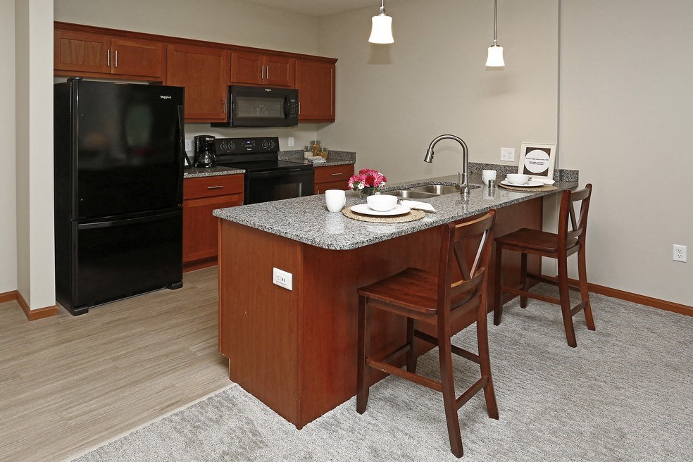 a kitchen with a island and a black refrigerator