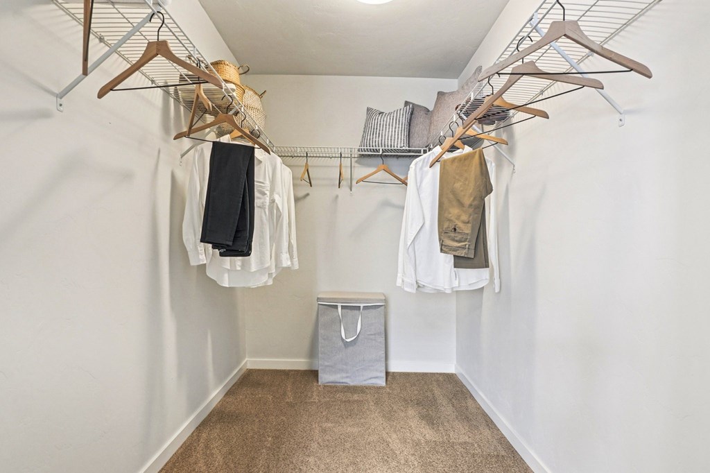 A white closet with clothes hanging and a bag on the floor. at Connect at First Creek Apartments, Denver, Colorado