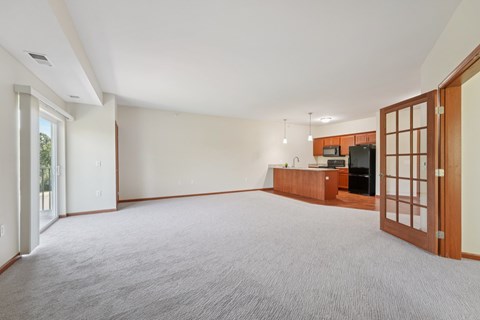 A spacious living room with a grey carpet and a wooden cabinet.