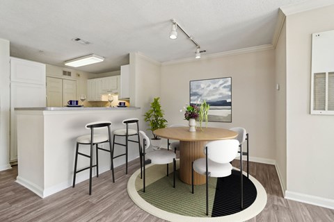 A kitchen with a bar and a dining table with chairs.