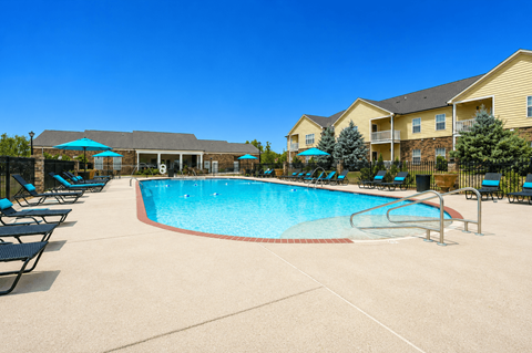 A large swimming pool surrounded by lounge chairs and umbrellas.
