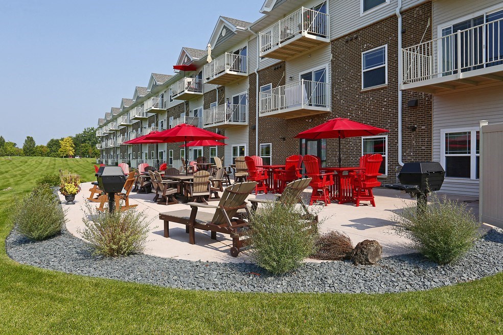 a patio with tables and chairs in front of an apartment building