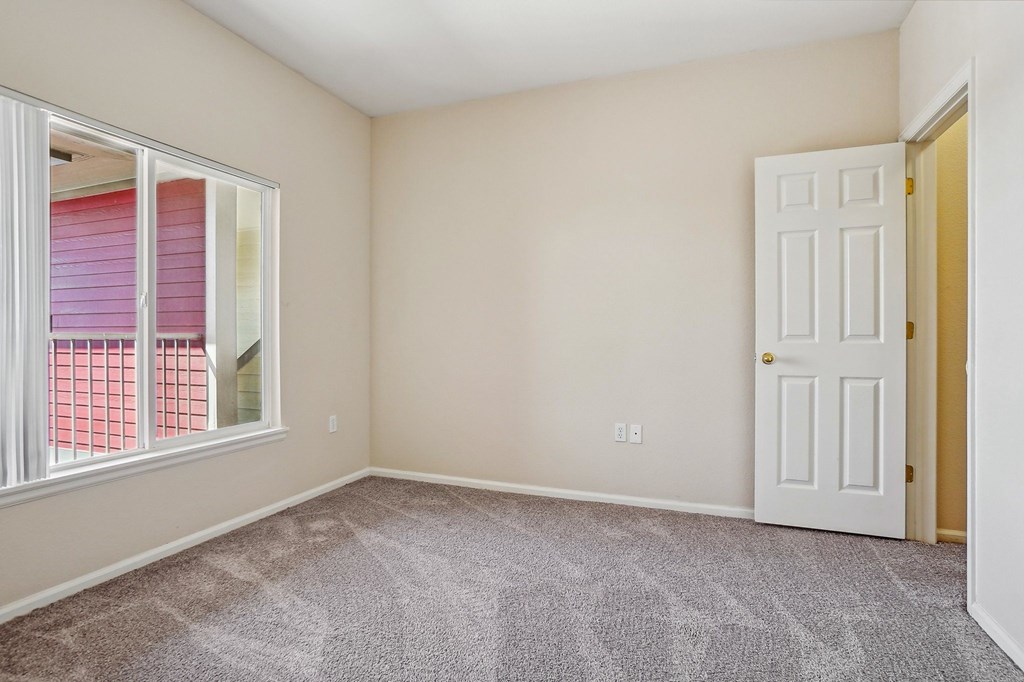A room with a carpeted floor, a white door, and a window with pink blinds. at Stetson Meadows Apartments, Colorado