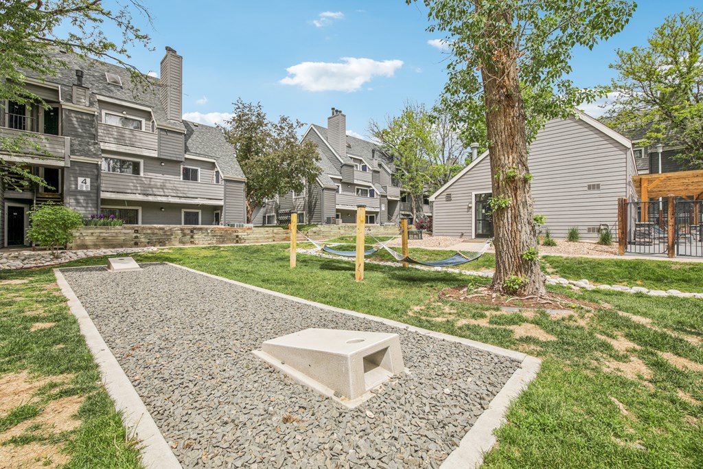 A gravel area with a white square in the middle and a tree to the right.