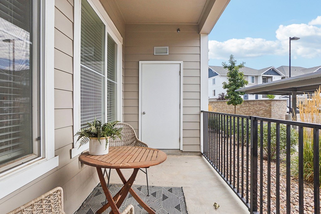 A small balcony with a table and chairs. at Connect at First Creek Apartments, Denver