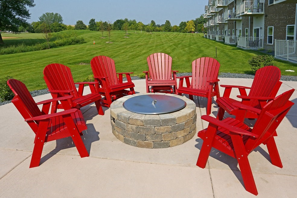 a fire pit with red chairs around it on a patio