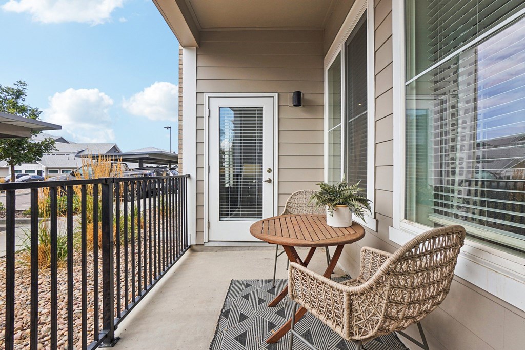 A patio with a wicker chair and table at Connect at First Creek Apartments, Denver, CO, 80249