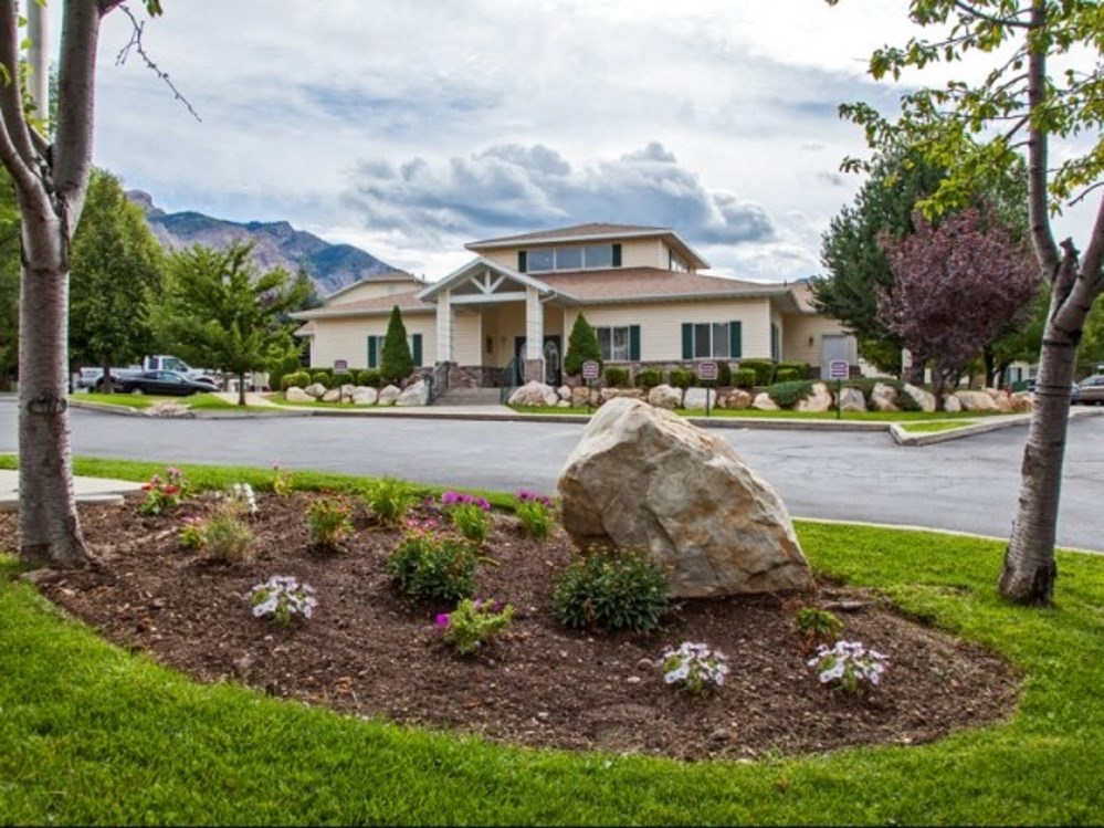 a home with a rock and flowers in the front yard