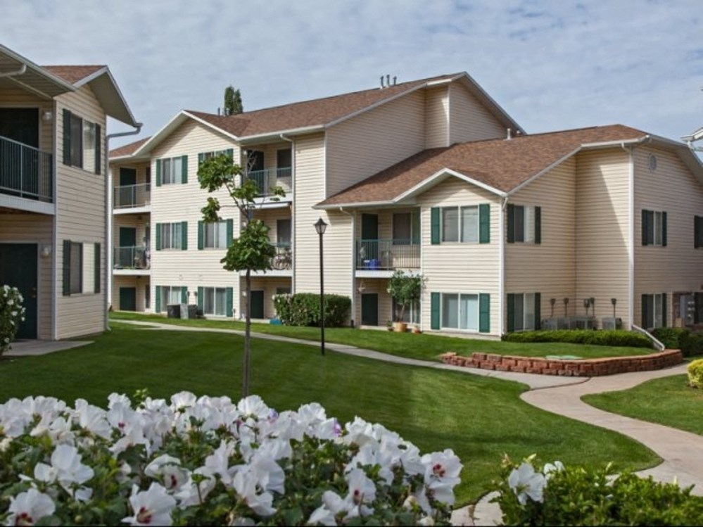 an apartment building with grass and flowers in front of it