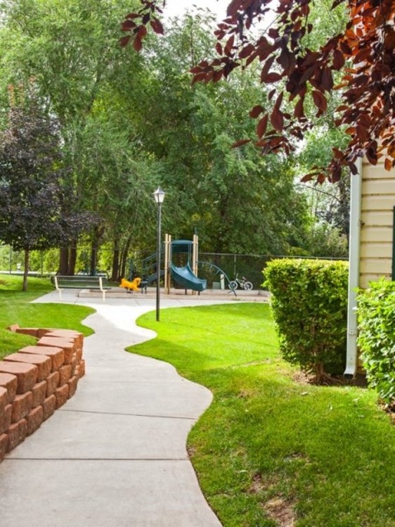 a sidewalk leading to a playground in a park
