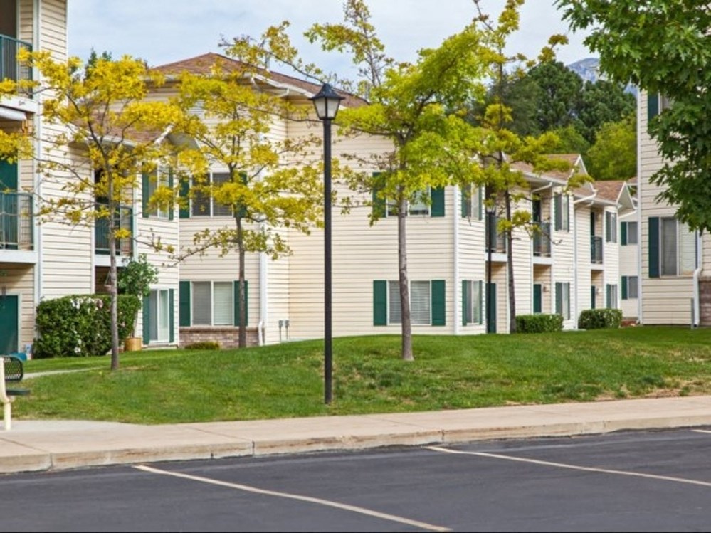 a row of white apartments with green shutters and a street light in front