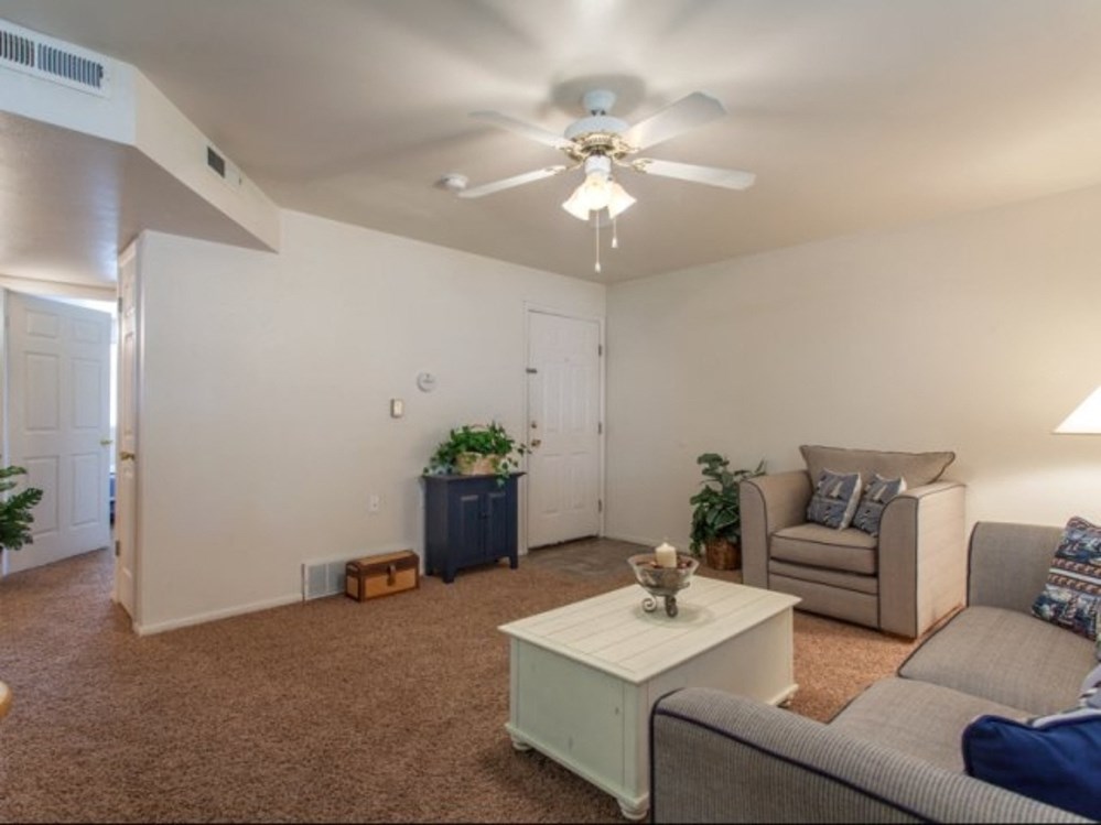 a living room with couches and a coffee table and a ceiling fan