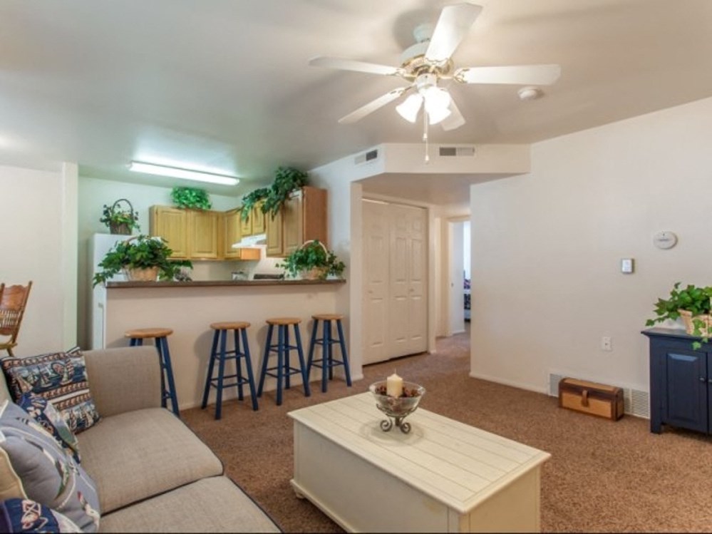 a living room with a couch and a bar and a ceiling fan