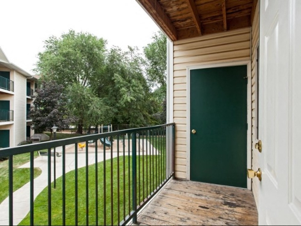 the view of the yard from the balcony of a home with a green door
