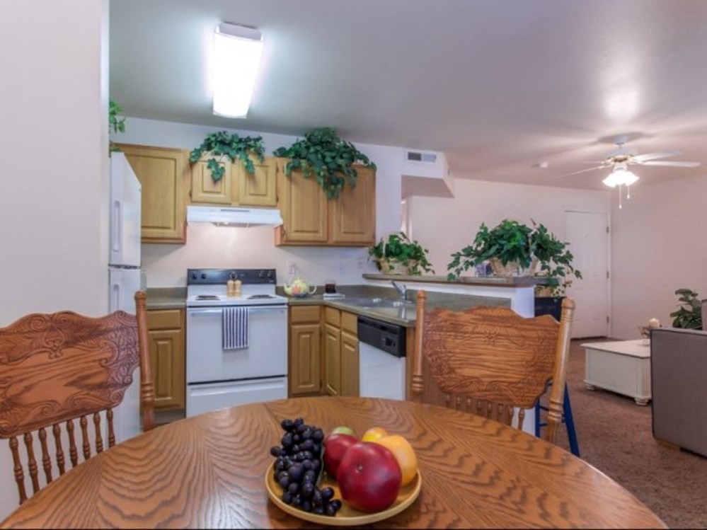 a kitchen and dining room with a bowl of fruit on the table