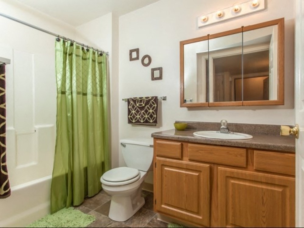 a bathroom with a green shower curtain and a toilet