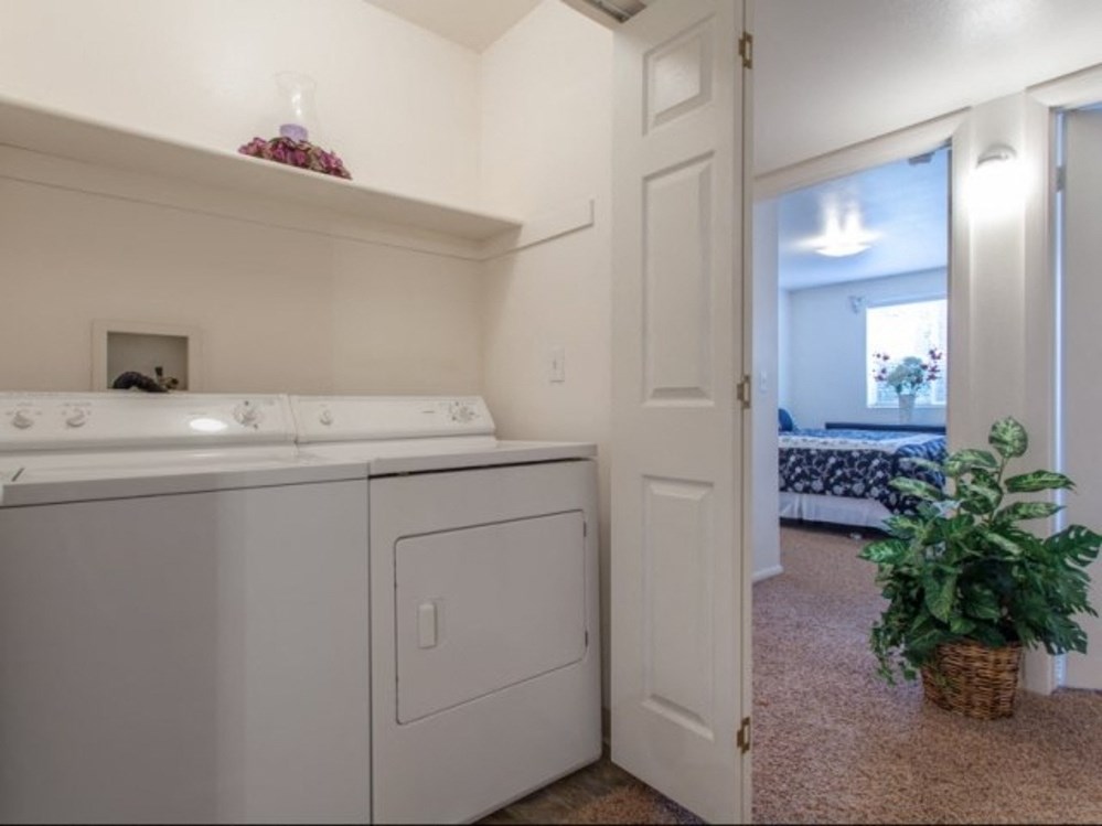 a white washer and dryer in a room with a door to a bedroom