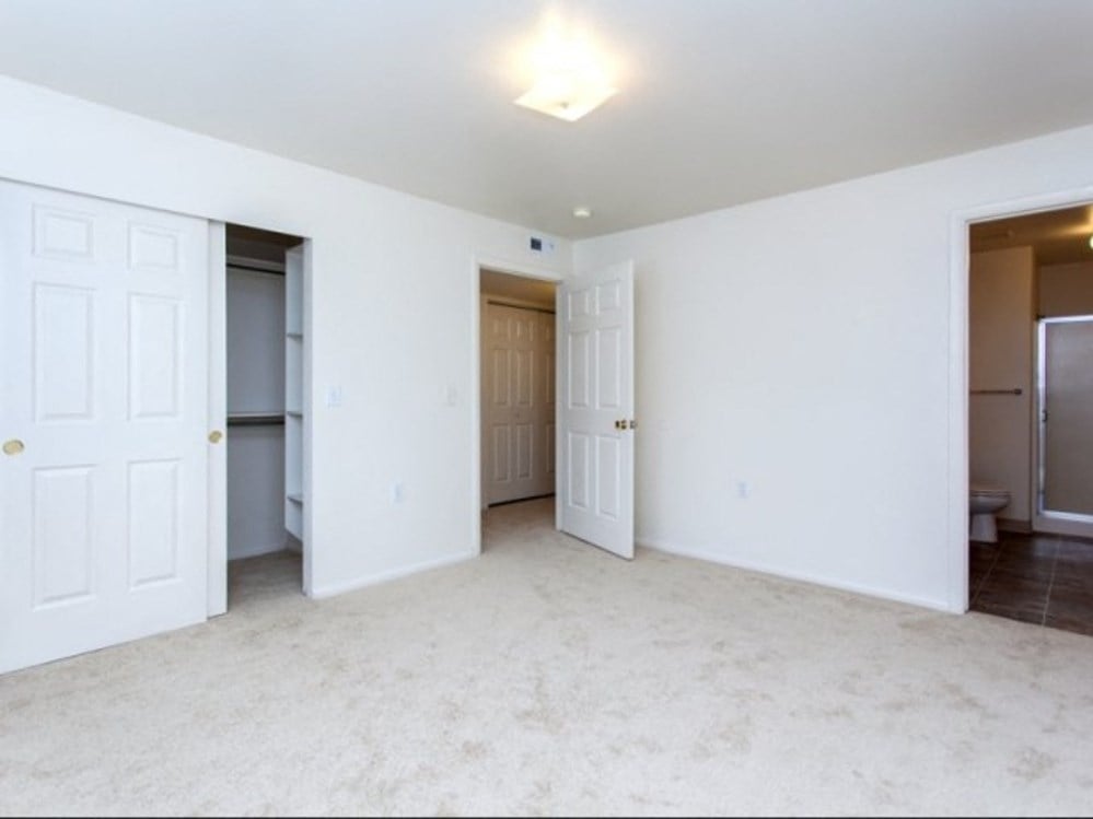 an empty living room with two closets and two doors