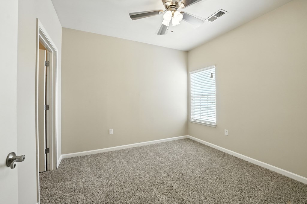 A room with a ceiling fan and a window with blinds.