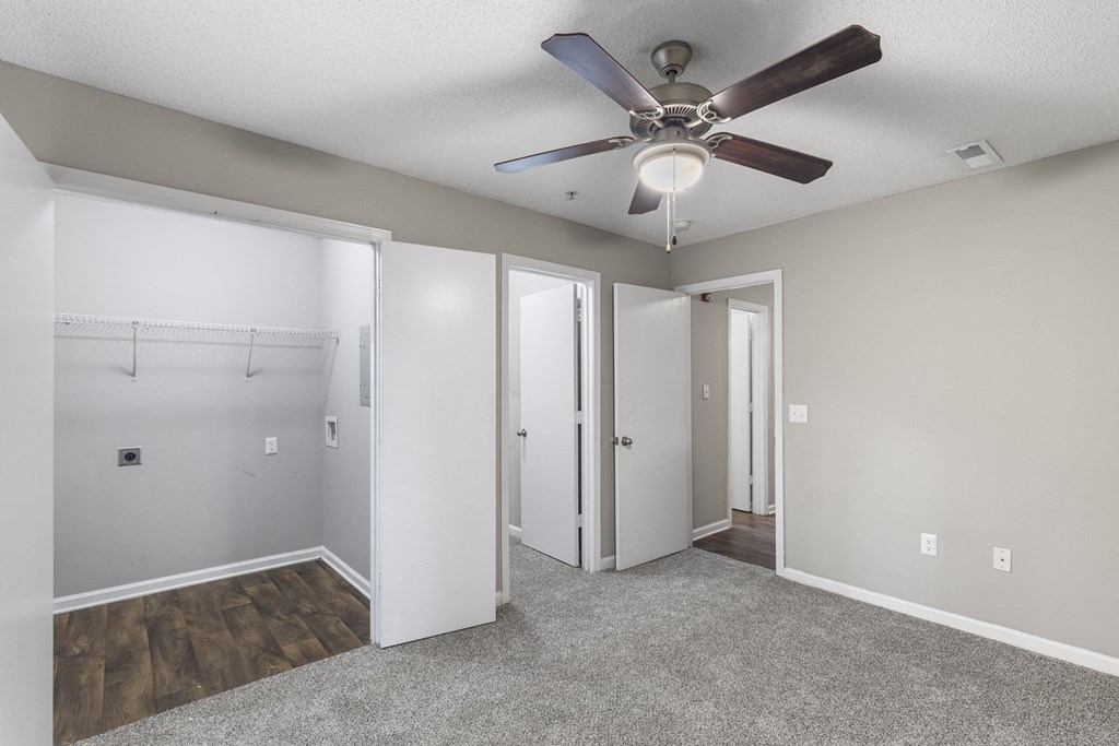 an empty bedroom with a ceiling fan and a closet