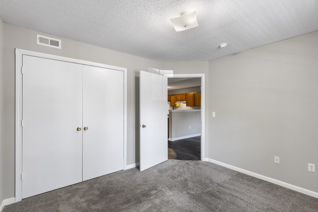 a bedroom with white closets and a door to a kitchen