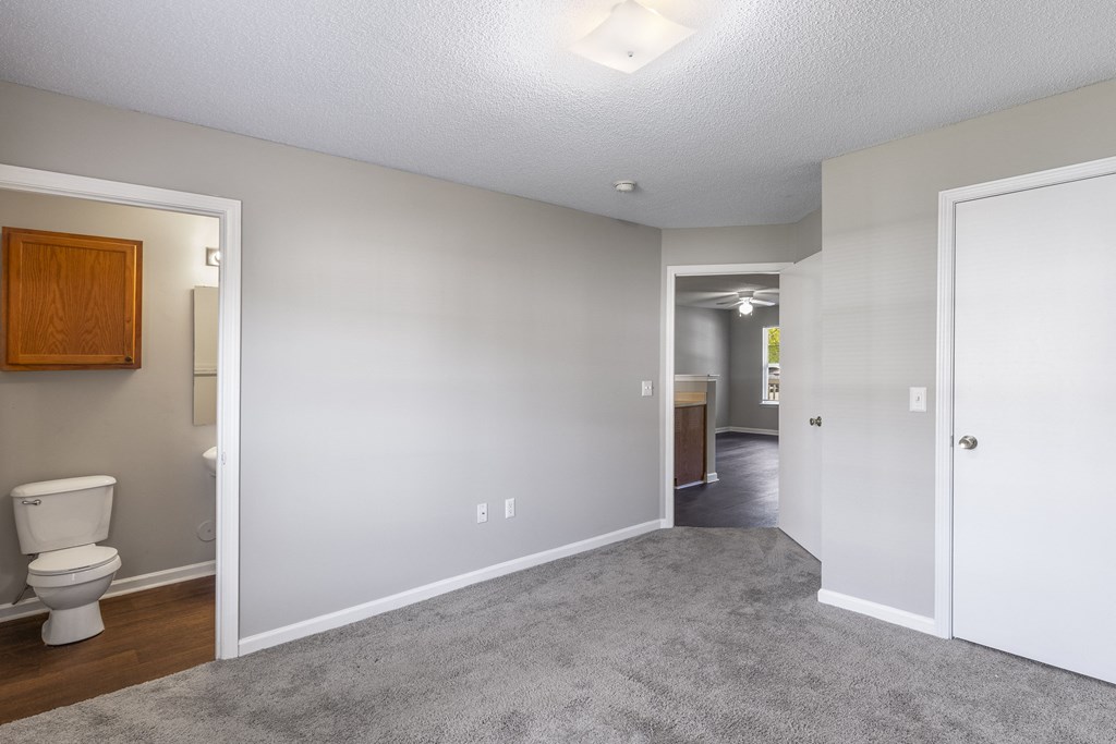 an empty room with a toilet and a hallway to a bathroom