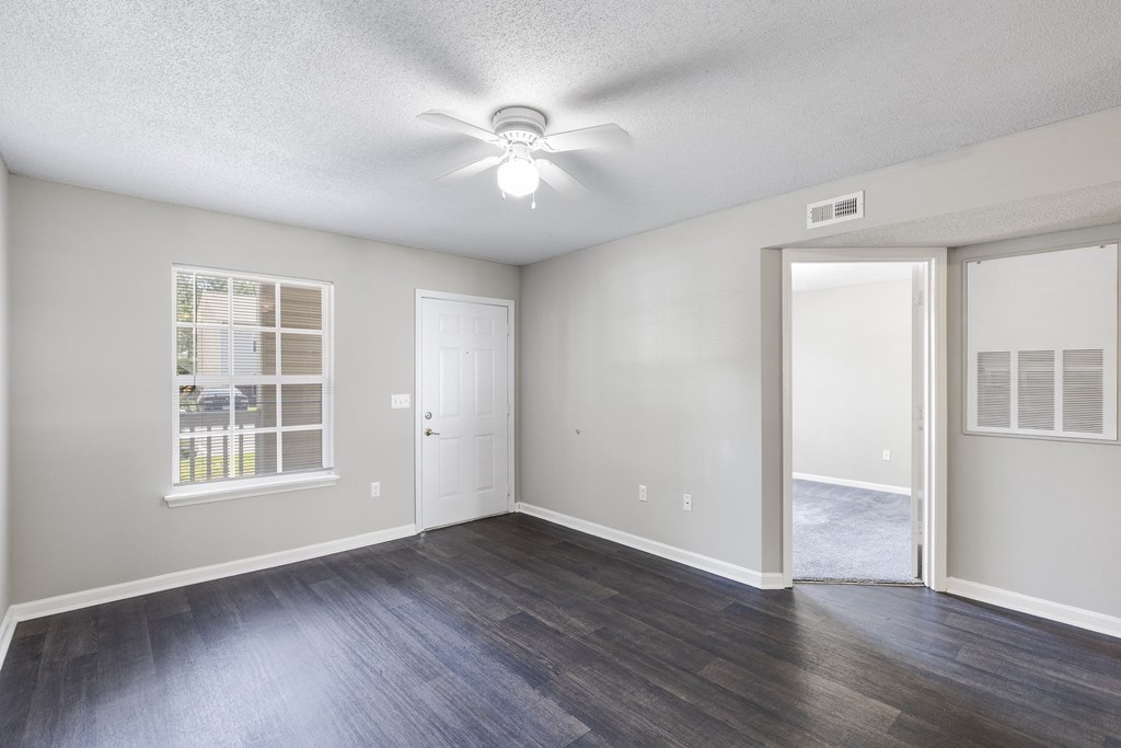 an empty living room with a ceiling fan and a window