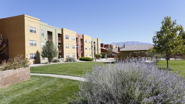 an apartment building with a green lawn and a sidewalk