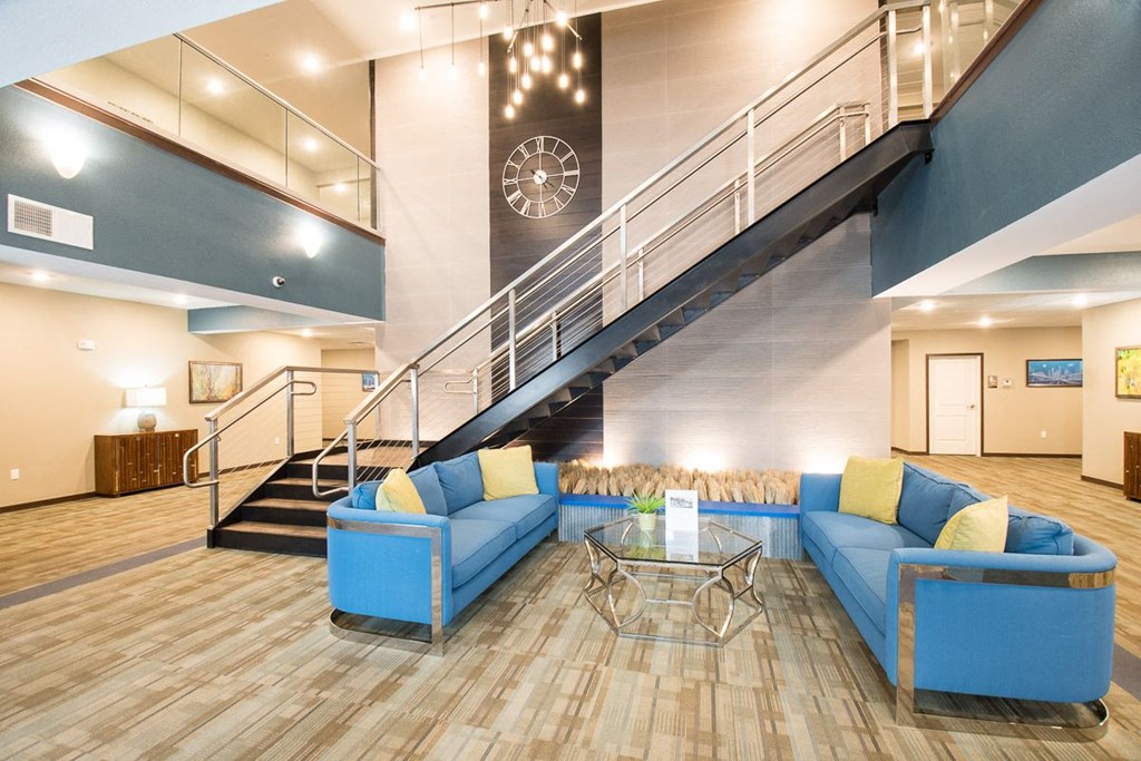 a lobby with blue couches and a glass table