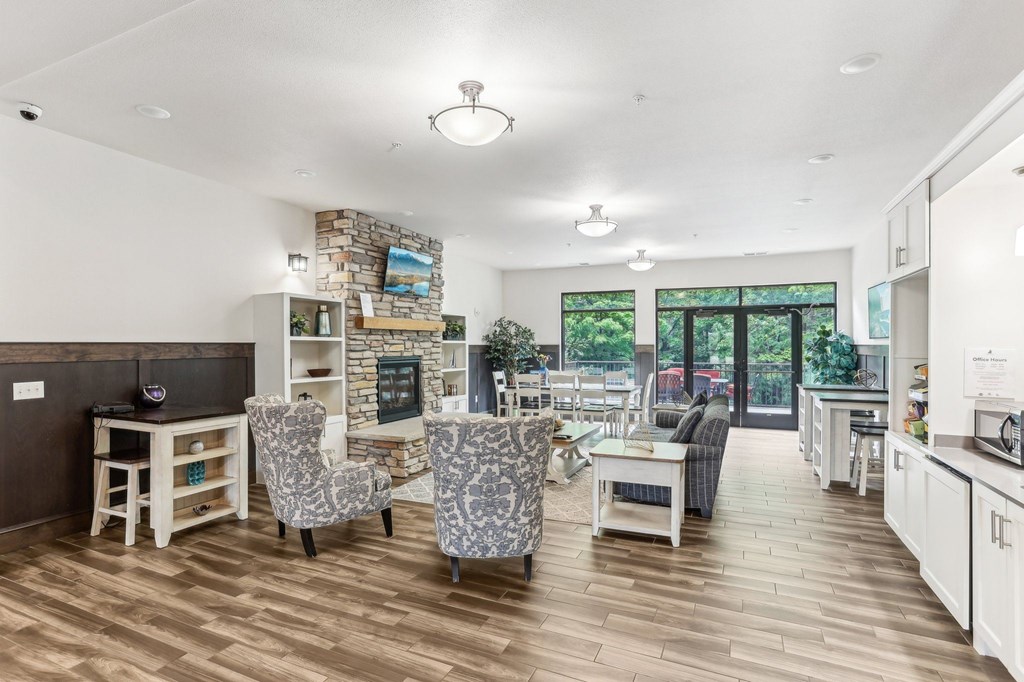 A modern living room with a stone fireplace and wooden floors. at Lake Ridge Apartments, Prior Lake, MN, 55379