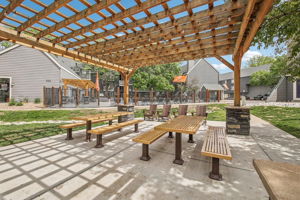 A wooden pergola with benches is in the foreground of the image.