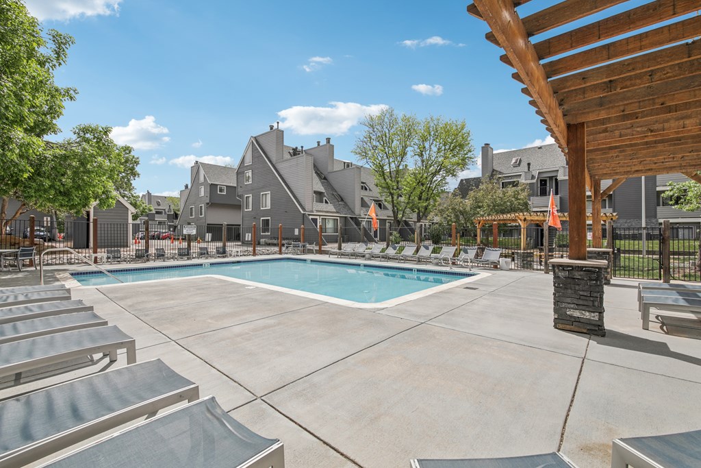 A large outdoor swimming pool surrounded by lounge chairs and umbrellas.