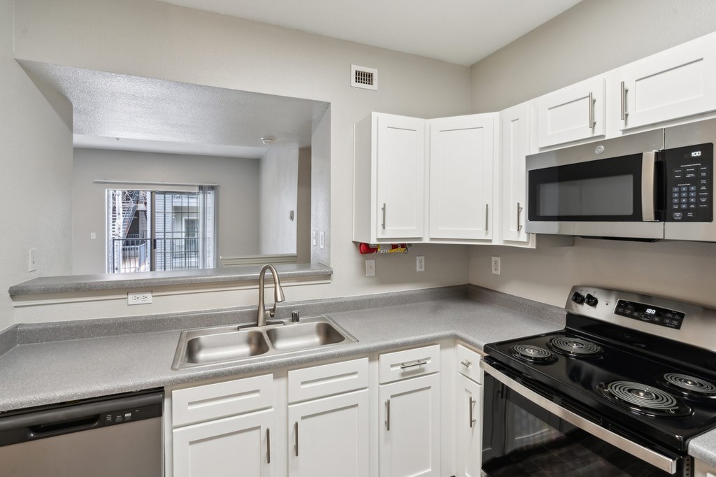 a kitchen with white cabinets and black appliances and a window