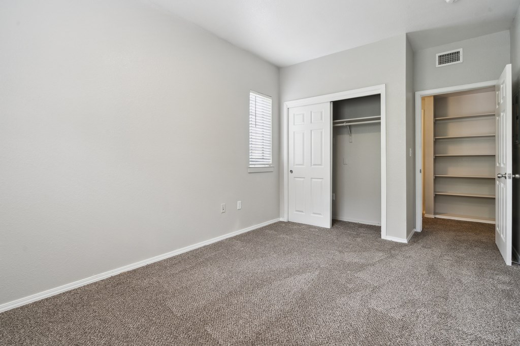 an empty bedroom with a closet and a door to the bathroom
